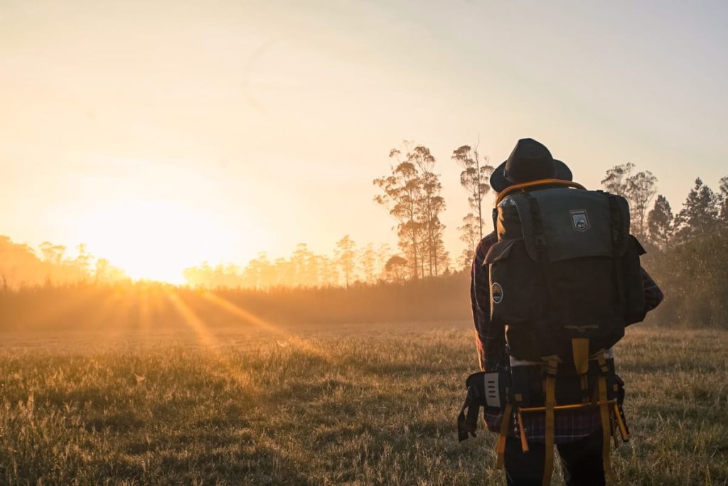 ein mann mit rucksack der den Sonnenuntergang anschaut