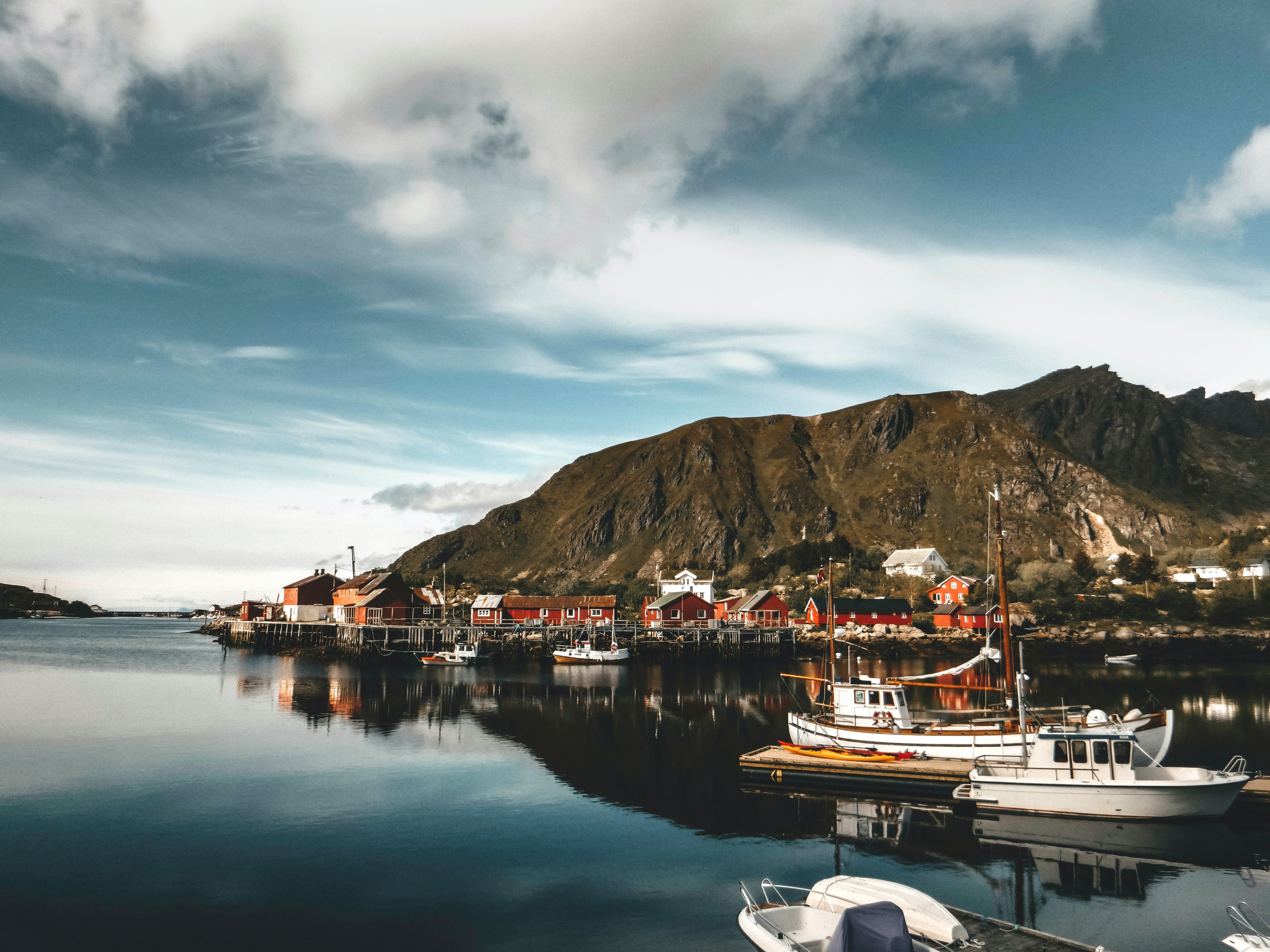 Norway is a covid alternative travel destination with fishing boats in the sea and wooden red houses.