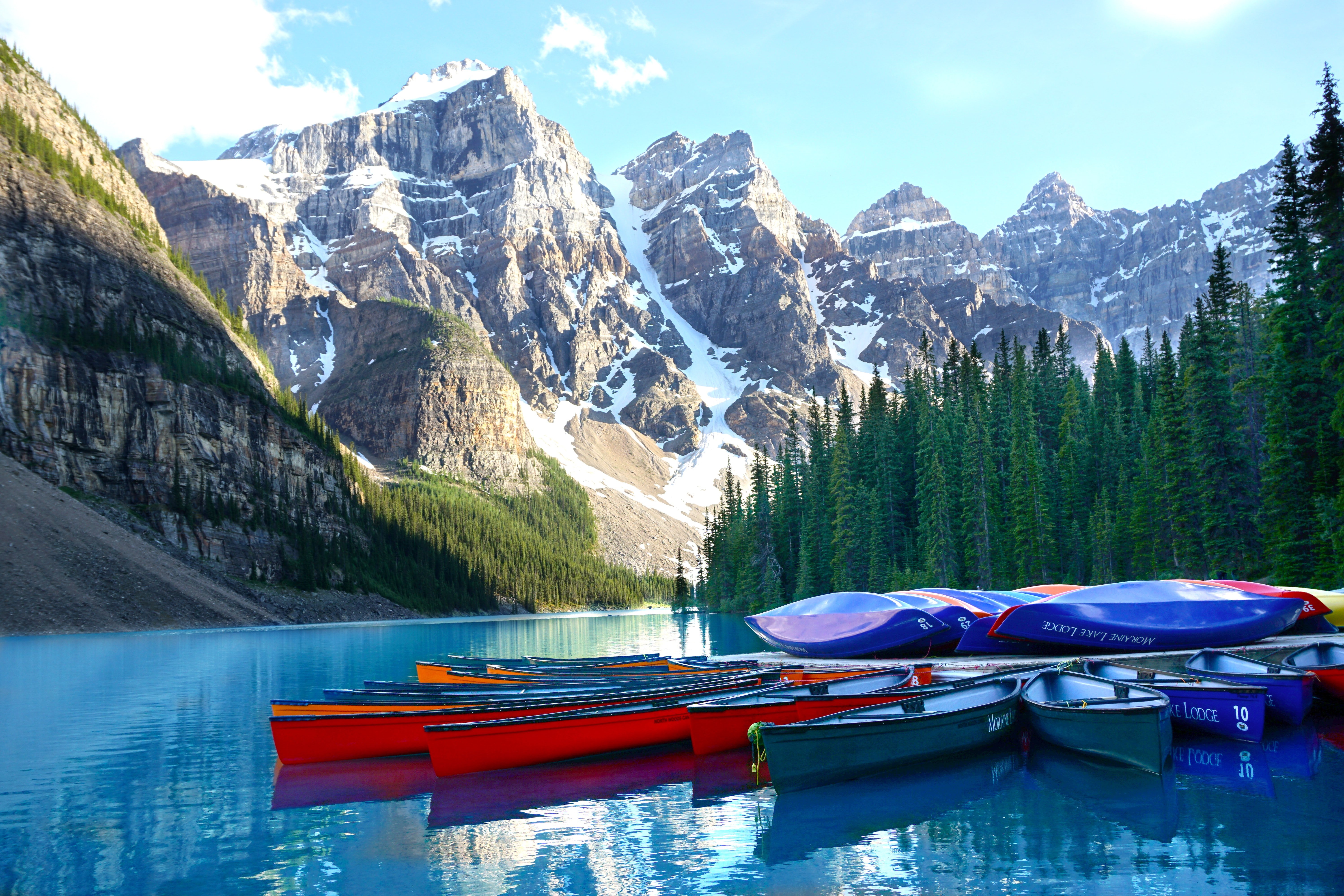 Canoes on blue waters with mountains and trees in the background
