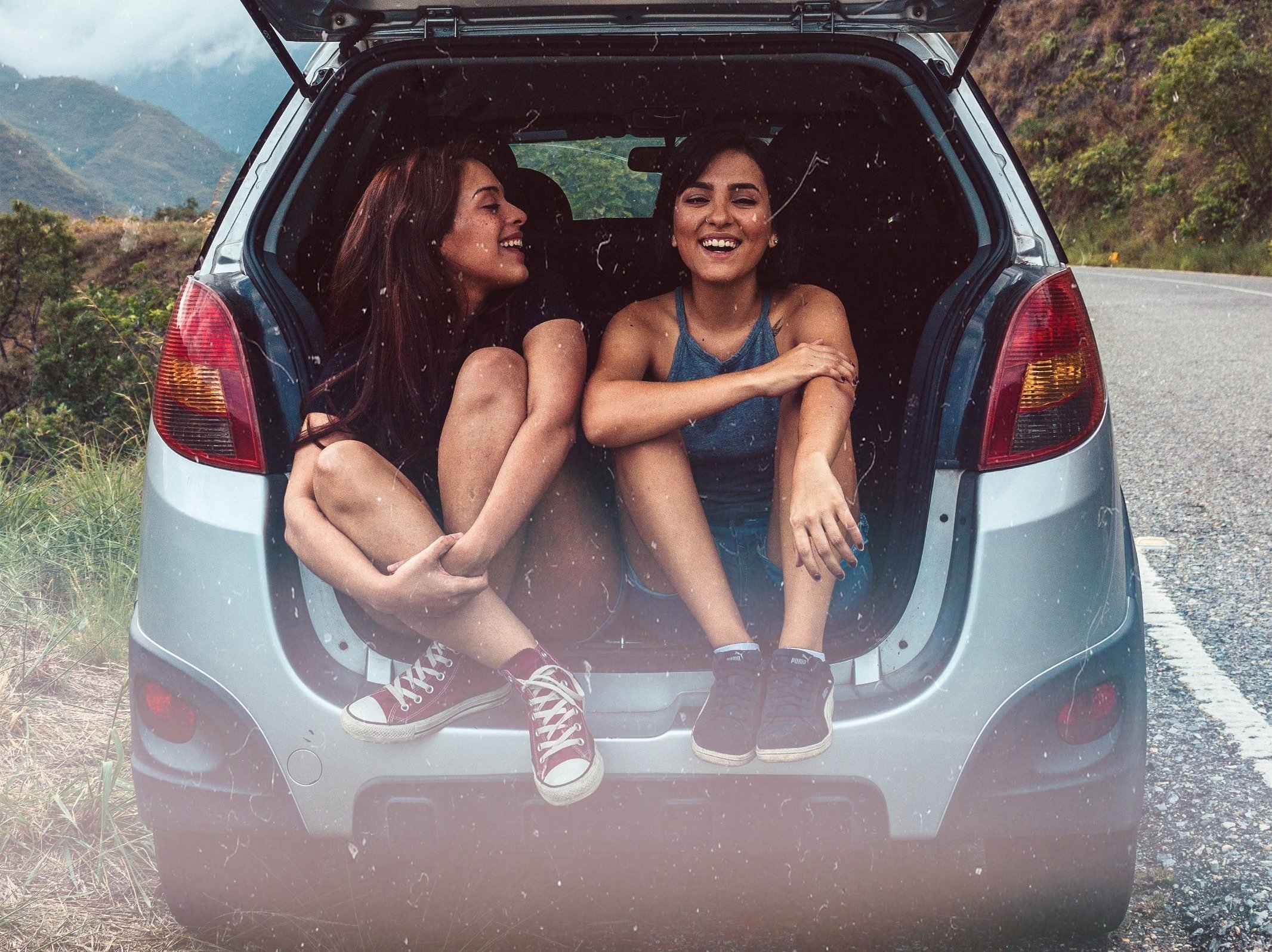 Two girls sitting in the back of a car on a group trip.