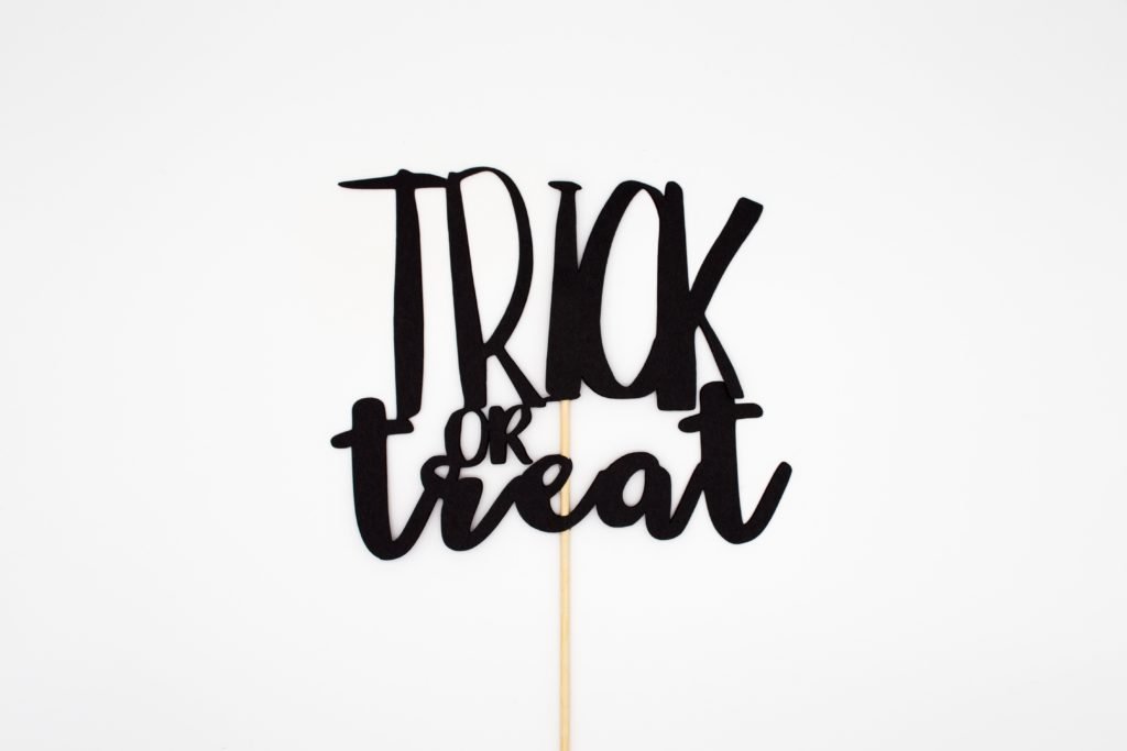 Ein Schild wird hochgehalten mit dem Satz: trick or treat