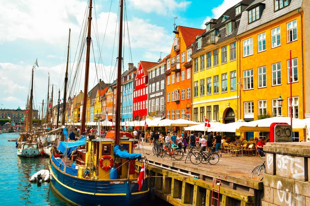 a view of Copenhagen in Denmark with sailing boats shipped alongside the colourful buildings.