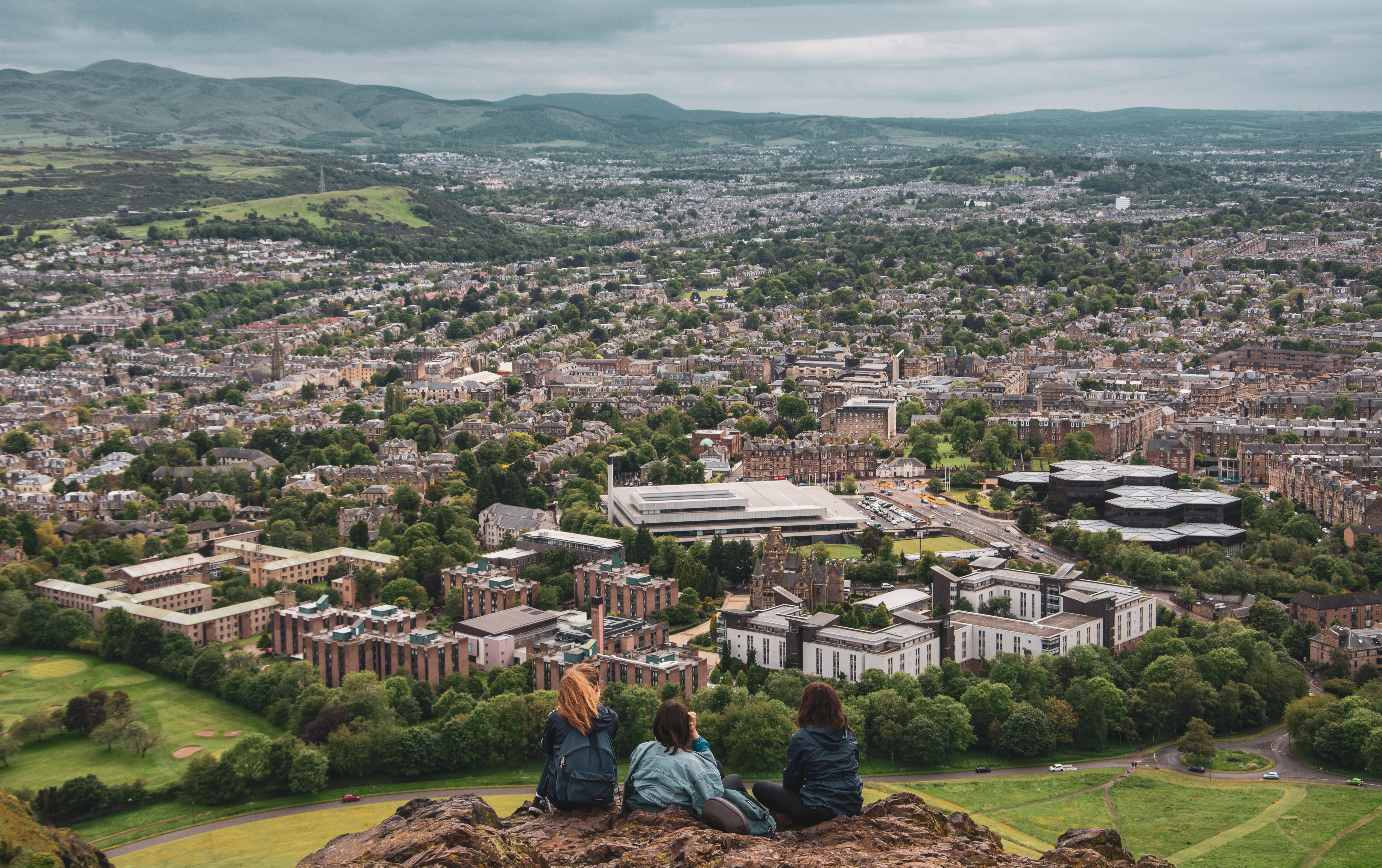 Three people looking out at the medieval city of Edinburgh from above
