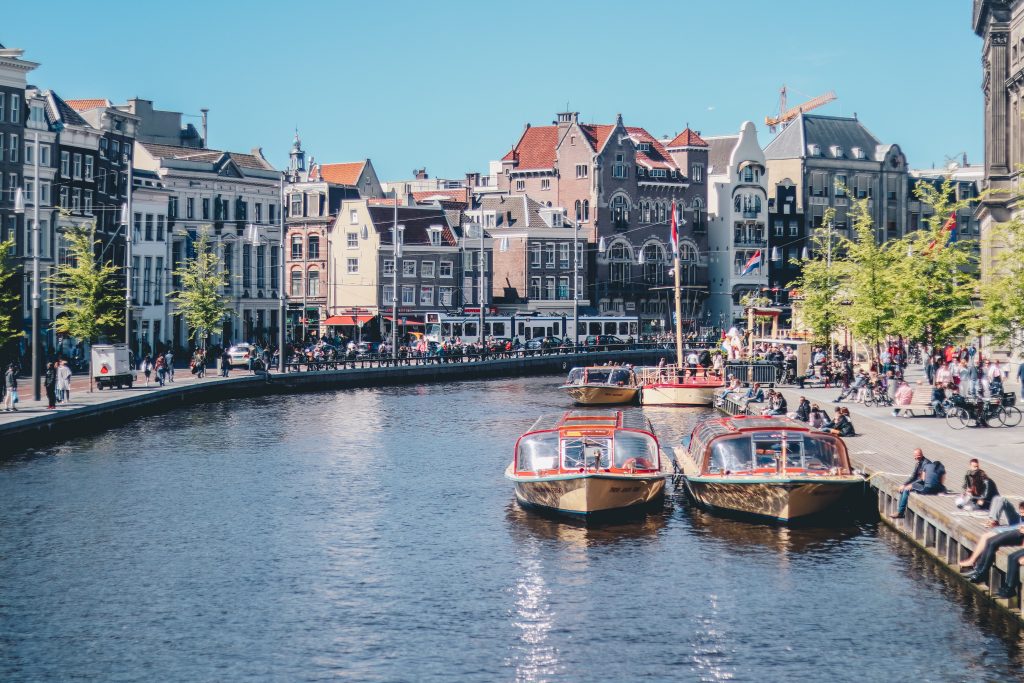 a view of the Amsterdam canals with buildings and boats on the water.