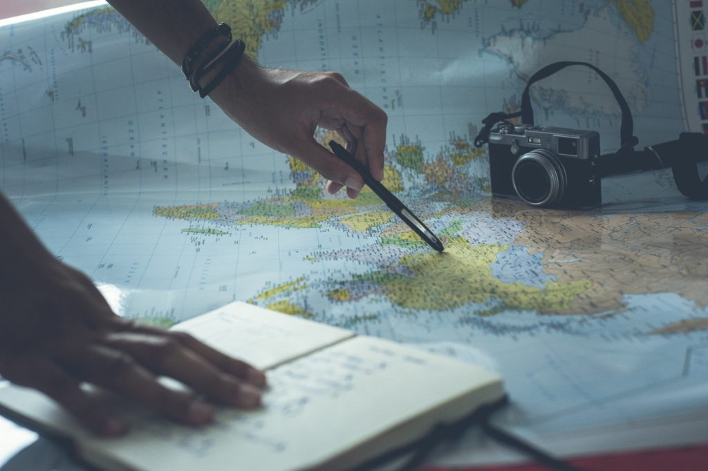 a picture of a person holding a pen against a map and a notepad while planning a short trip
