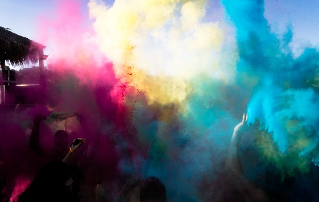 Farben werden von Menschen hochgeworfen und bilden einen Regenbogen - Holi Festival in Indien 