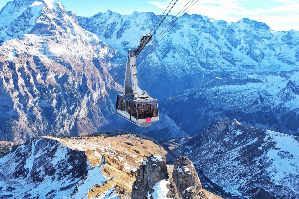 Eine Gondel schwebt über den schneebedeckten Bergen der Schweiz
