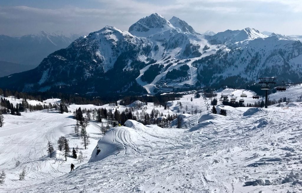 Hohe schneebedeckte Berge und inmitten ein Skigebiet in Österreich