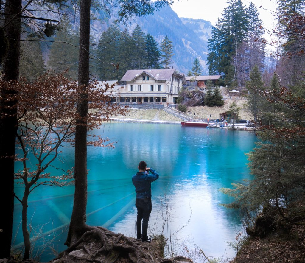 Ein Mann macht Fotos vom Blausee, der türkisblau und kristallklar ist. 