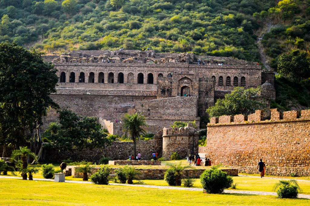 Bhangarh Fort in Rajasthan, India during the day time with luscious greenery around ghost towns