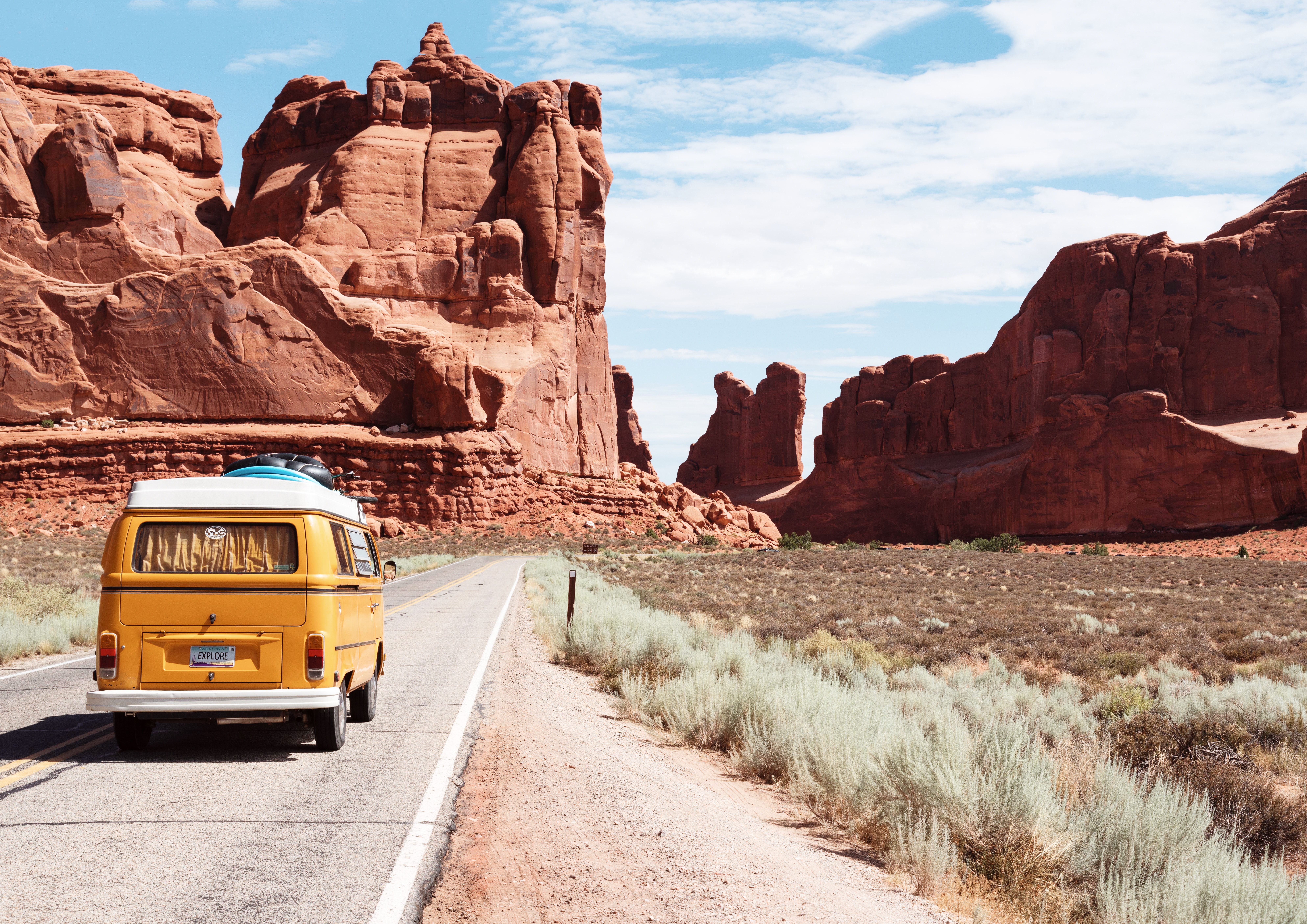 A yellow roadtrip van in a dry rocky landscape travel words