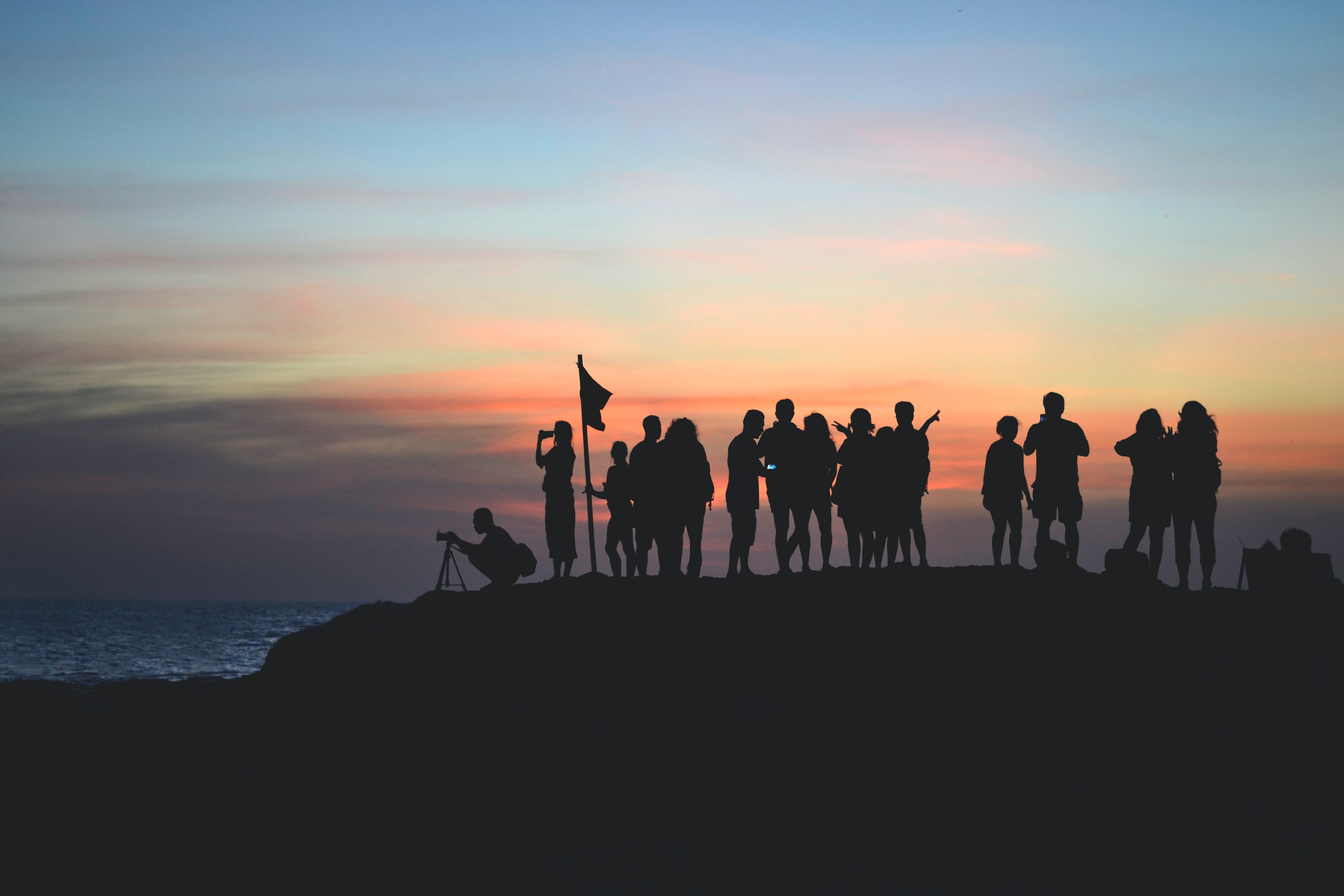A group of people on top of a mountain in the sunset.