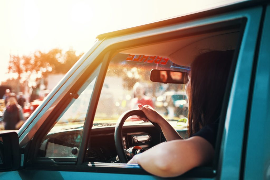 a woman driving on a roadtrip in a blue car 