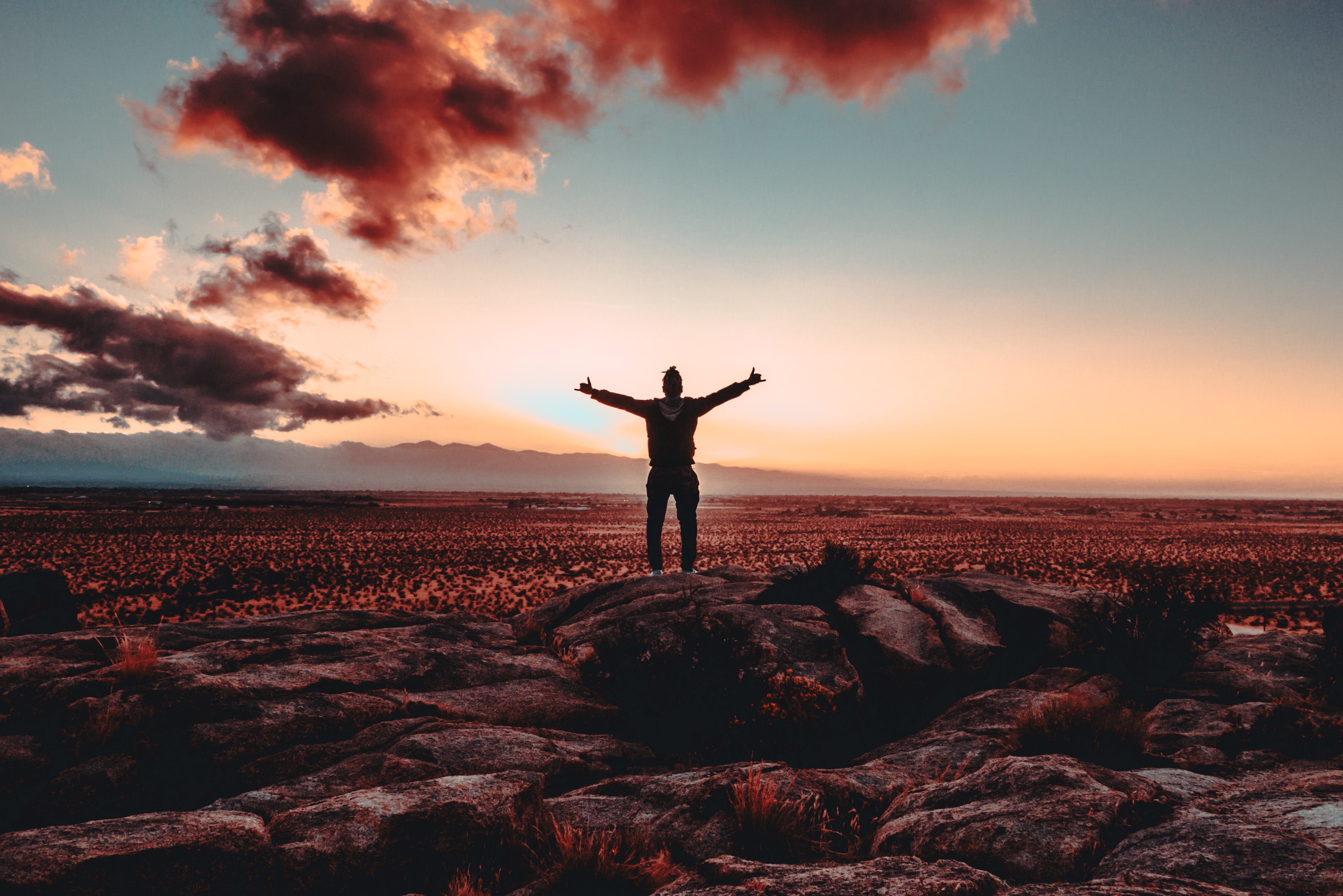 A man standing on top of rocks in the sunset.