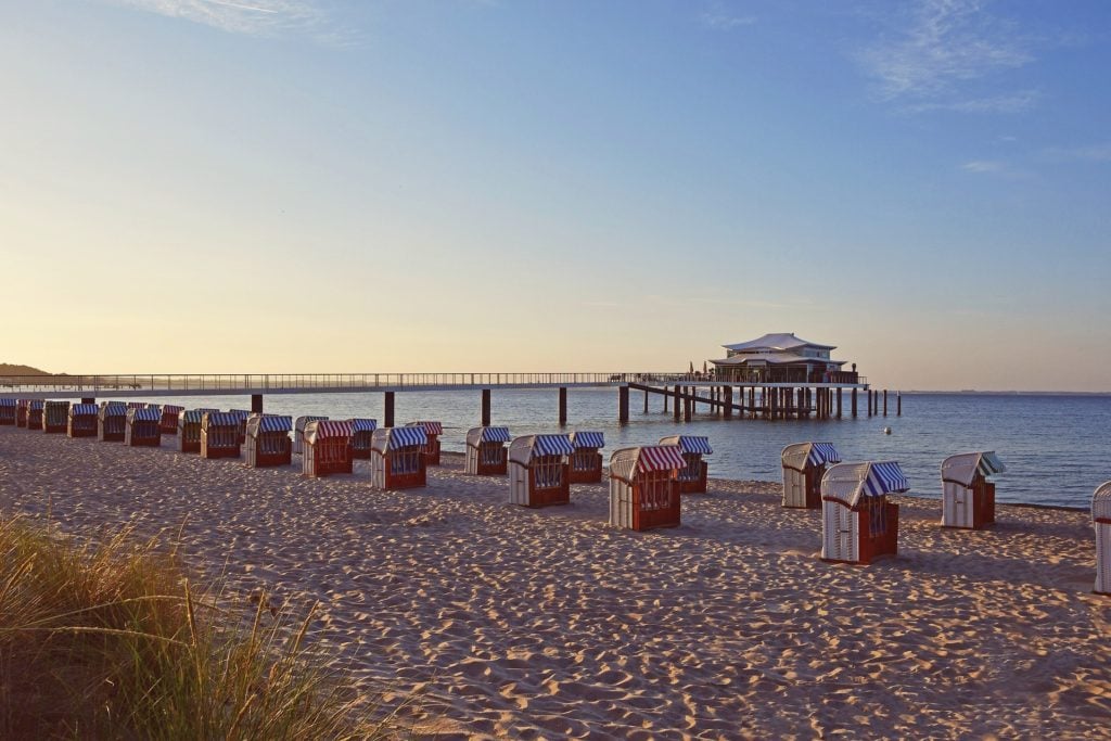 Der Steg zum japanischen Teehaus in Timmendorf Strand im Sonnenuntergang, mit Strandkörben im Vordergrund. Die Lübecker Bucht ist ein Surf-Spot an der Ostsee 