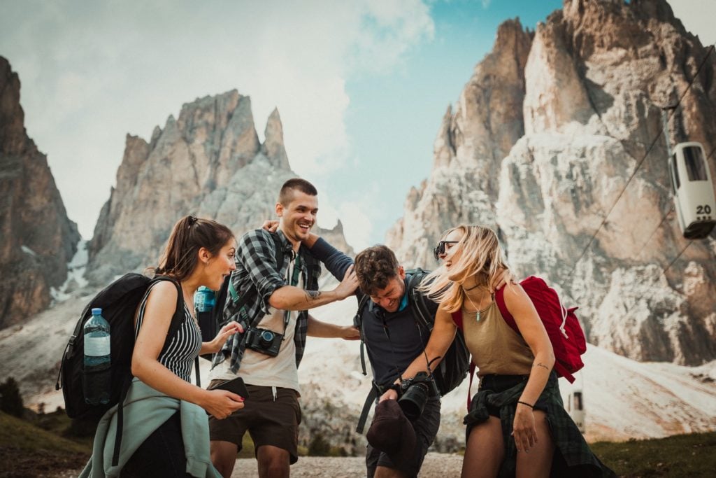 Rucksack-Tipps: Je zwei fröhliche Männer und Frauen mit Rucksäcken vor felsiger Landschaft 