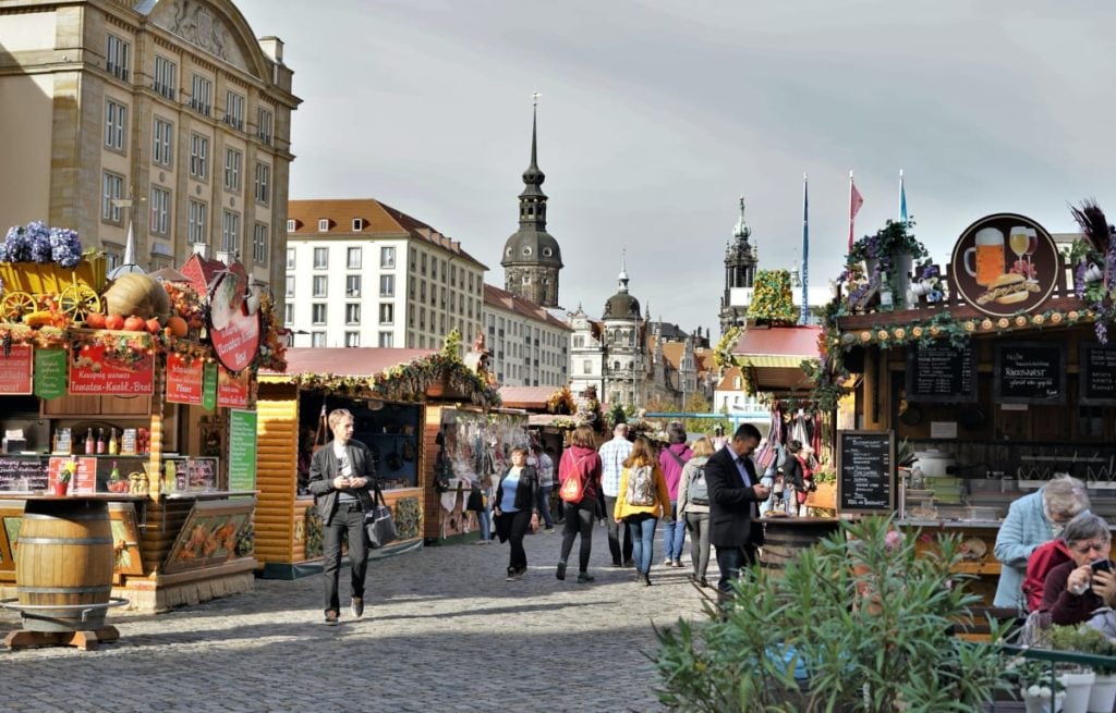 Der Marktplatz in Dresden mit einem Wochenmarkt und einer Kirche im Hintergrund. Dresden ist perfekt für einen günstigen Studententrip. 