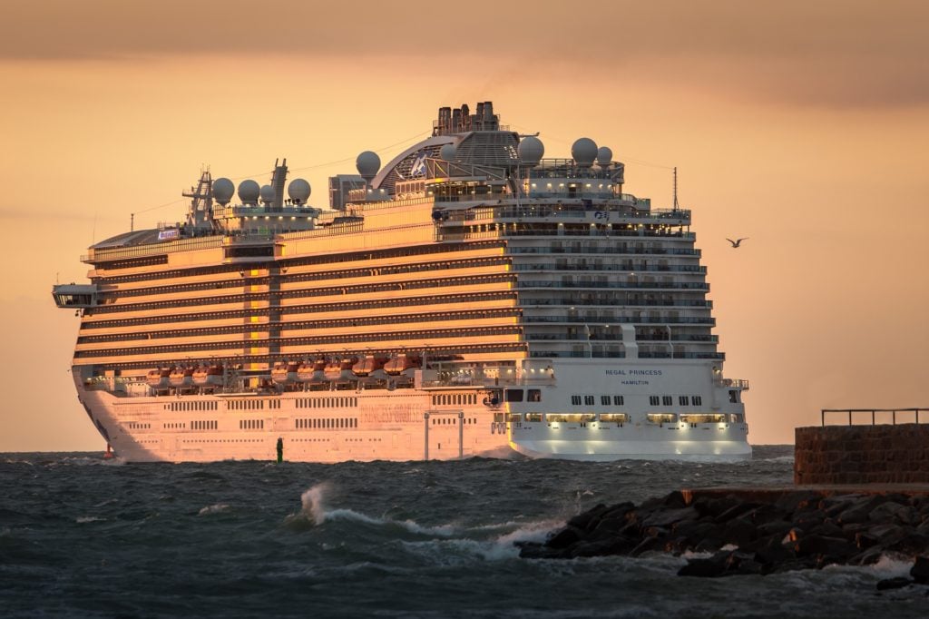 Das Kreuzfahrtschiff Regal Princess im Hafen von Warnemünde im Sonnenuntergang liefert große Wellen, die gut zum Fahrwellensurfing genutzt werden können 
