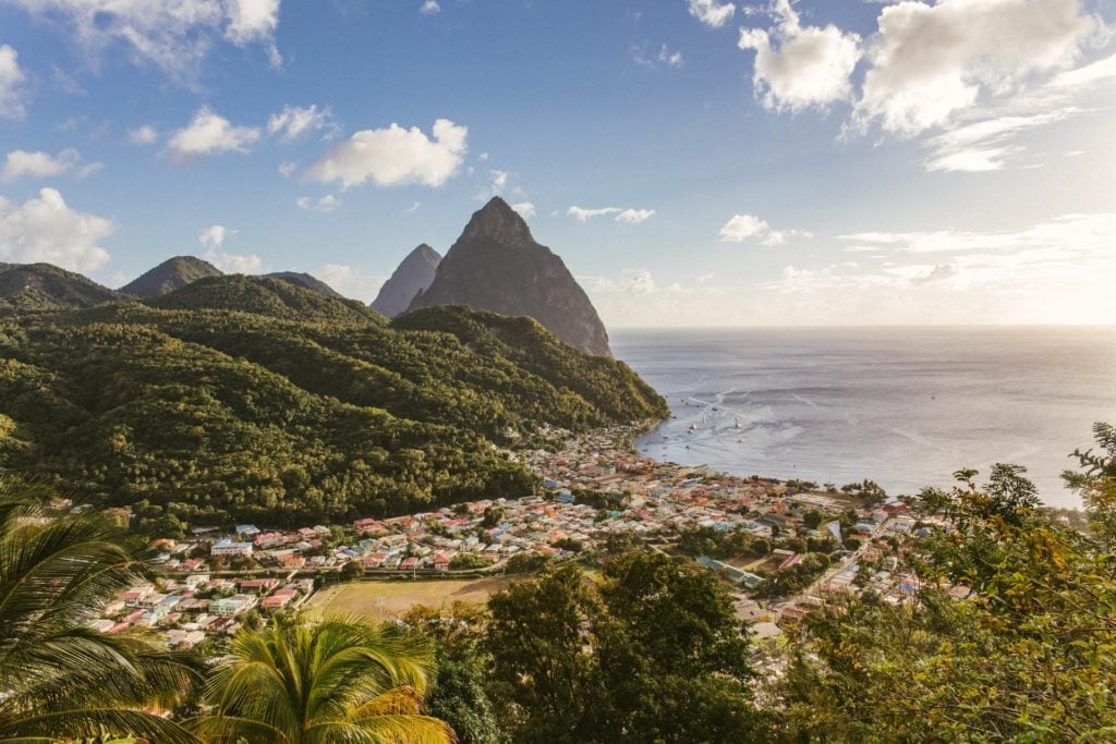 a view of a mountain next to the body of water and a town surrounded by beautiful nature, landscapes and water at the top St Lucia