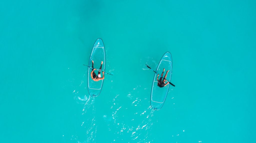 Two people sitting on paddleboards and talking to eachother while on the amazing turqoise water of the beautiful Grenada