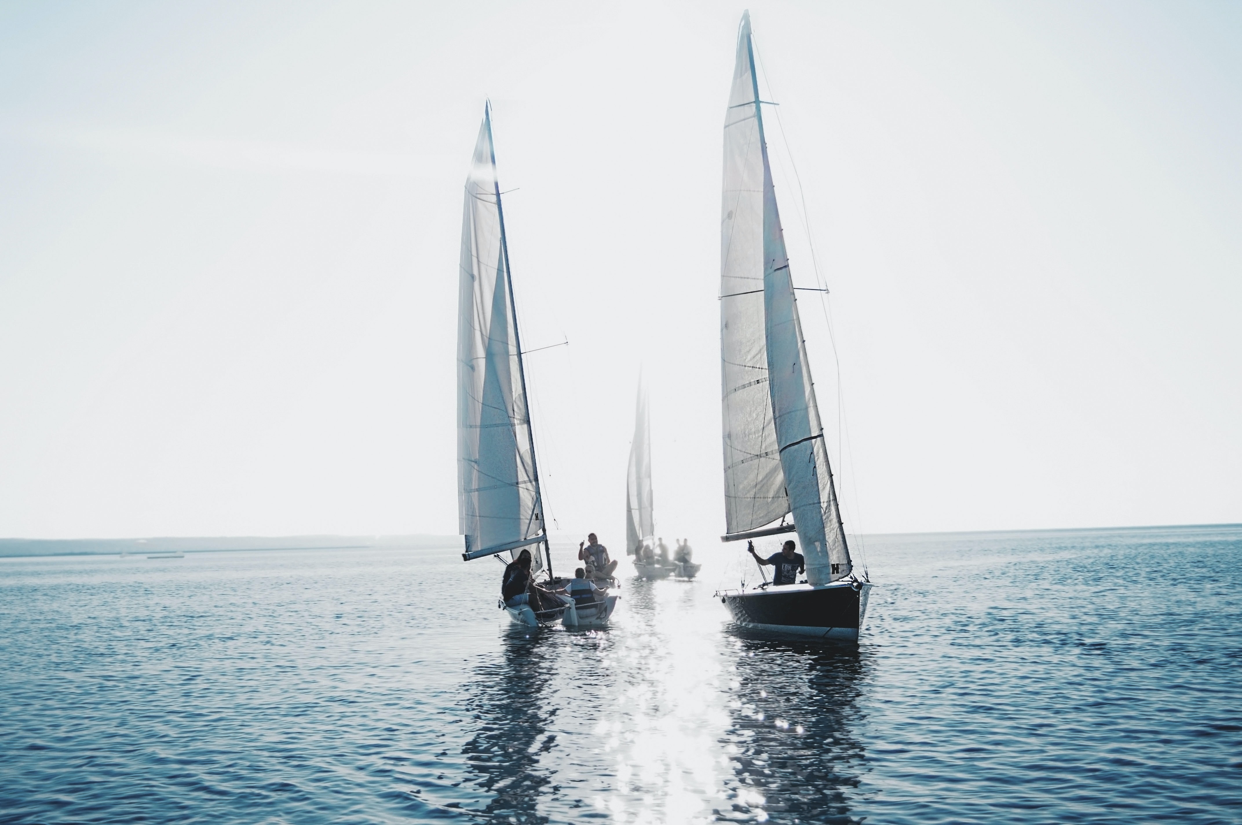 Three sailboats on the water with people. Sailing trips are special