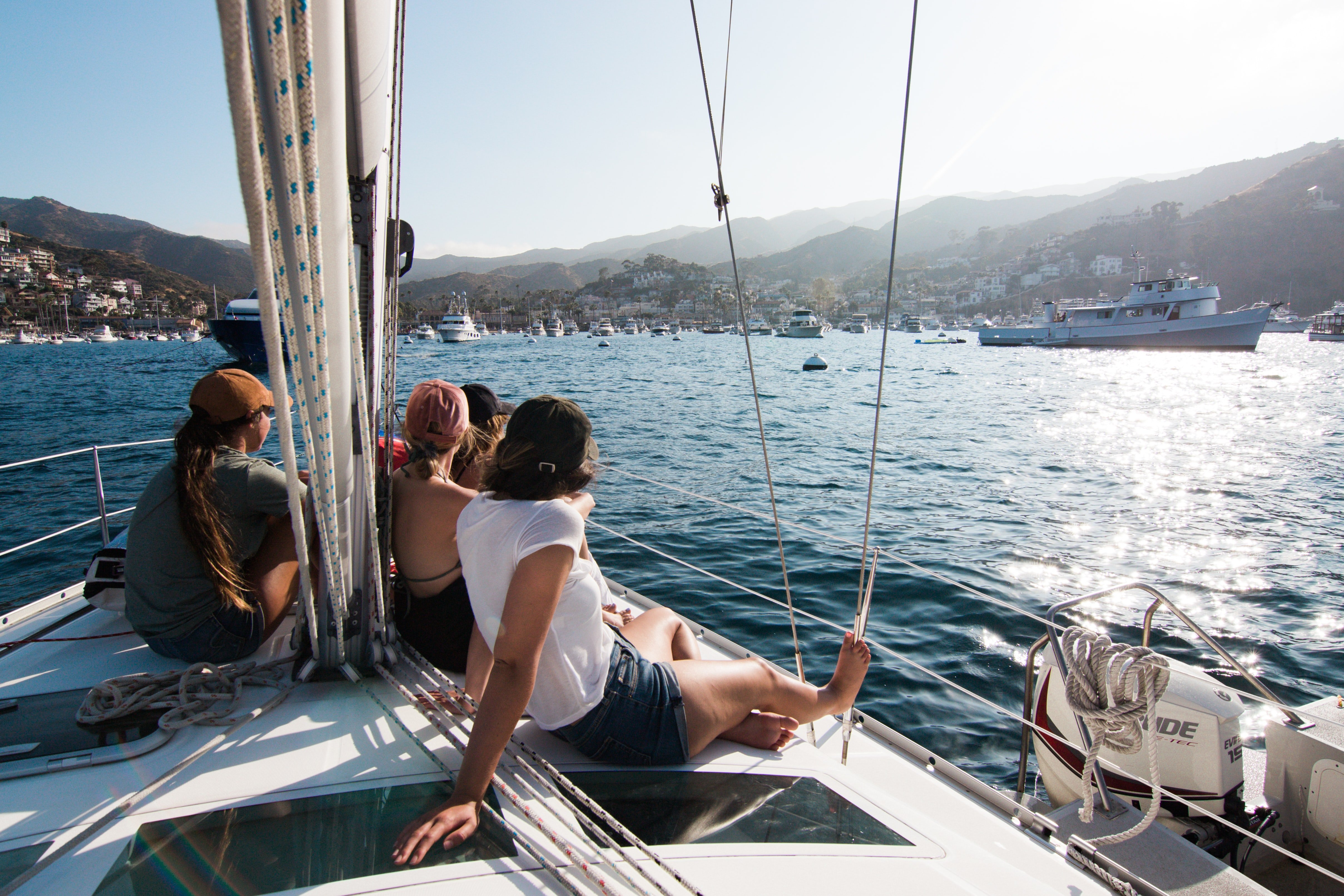 People relaxing on a sailboat in a mountainous scenery. Go on a sailing trip.