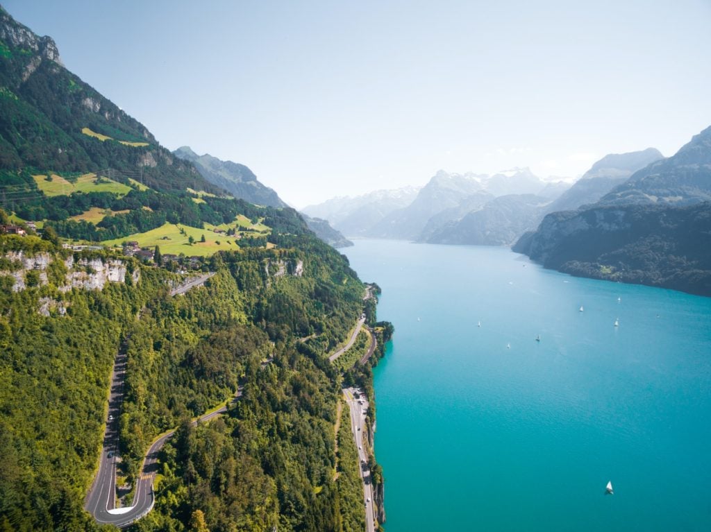 bird's eye photograph of Switzerland where there is bright blue water surrounded by mountains, perfect for hiking