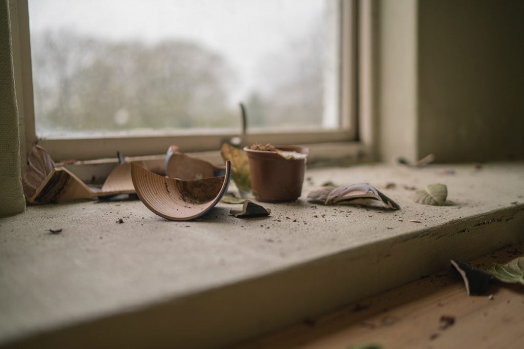 A beige broken pot by the window on a gloomy day.