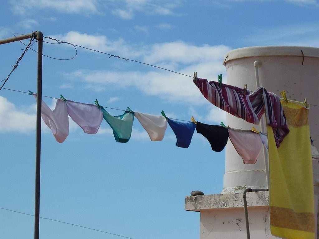 Coloured underwear on a drying line during the day with a blue sky.